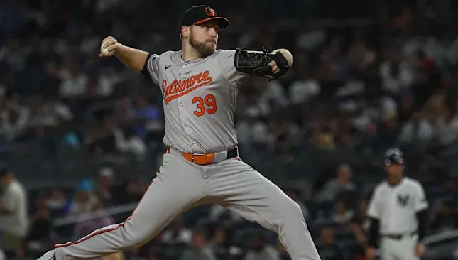 Baltimore Orioles pitcher wearing the gray away uniform from 2004 to the present, featuring orange ‘Baltimore’ script and black-orange trim, representing the modern era that revived the classic Cartoon Bird logo and blended traditional and contemporary design elements