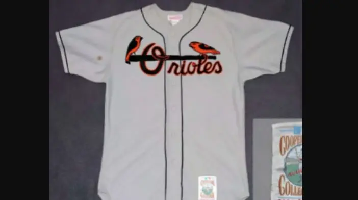 Baltimore Orioles road jersey from 1995–2003 in gray, featuring orange and black script ‘Orioles’ with bird graphics above the lettering, representing the era when black was added as an official team color.