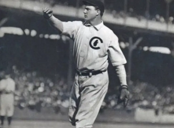 Chicago Cubs Jerseys 7 Early 1900s Chicago Cubs player in a white uniform with a large ‘C’ logo featuring a small bear inside, representing the team’s early bear logo era