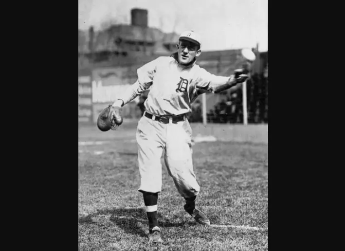 Detroit Tigers uniform from the early 1900s–1920s showing a player wearing a white flannel jersey with the classic Old English ‘D’ in navy blue on the chest — representing the team’s first iconic logo and the birth of Detroit’s navy and white color tradition