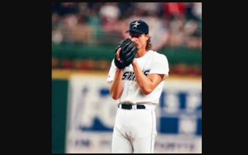 Houston Astros Jerseys 7 Houston Astros pitcher wearing white uniform with blue and gold ‘Astros’ script and gold star cap, representing the 1994–1999 navy and metallic gold rebrand era.