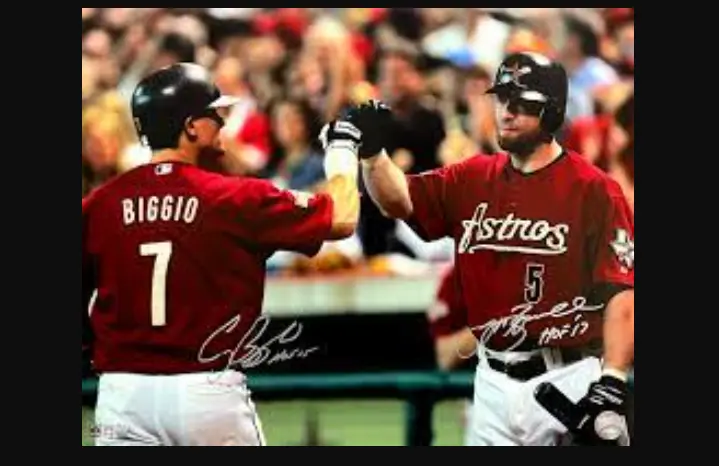 Houston Astros Jerseys 8 “Houston Astros players wearing brick red jerseys with cursive ‘Astros’ lettering, representing the 2000–2012 era featuring brick red and pinstripe designs