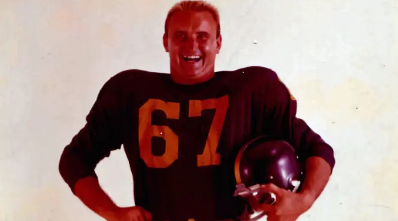 Titans of New York player wearing number 67 navy blue jersey and holding a gold helmet from the 1960–1962 era
