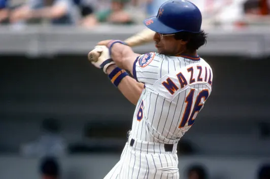 1978–1990 New York Mets player wearing the classic white pinstripe uniform with blue and orange racing stripes down the sides, swinging a bat — representing the ‘Racing Stripe’ and 1986 World Series championship era