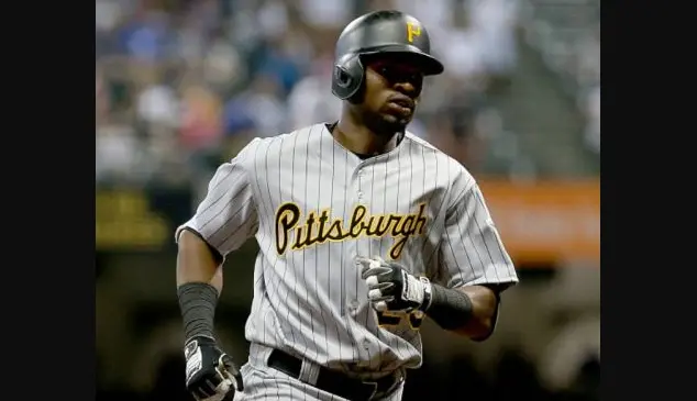 2001–present Pittsburgh Pirates away gray jersey with black and gold ‘Pittsburgh’ script, worn by player mid-run at PNC Park, representing the modern era featuring black and gold color scheme and updated designs