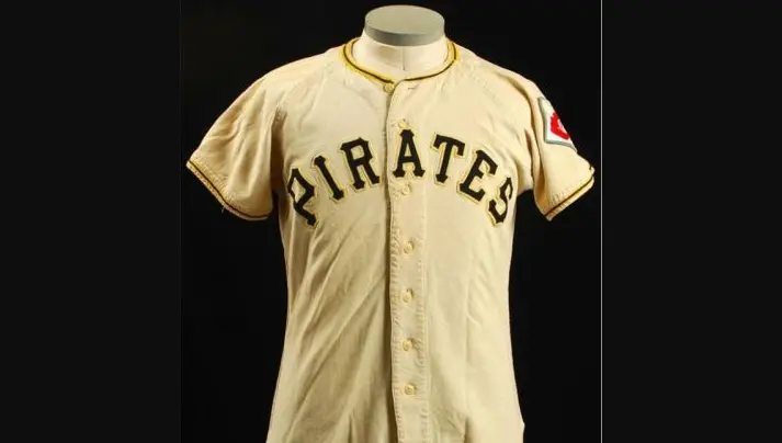 1948–1969 Pittsburgh Pirates cream-colored jersey featuring bold black ‘PIRATES’ lettering with gold trim and sleeve patch, marking the introduction of the team’s iconic black and gold colors