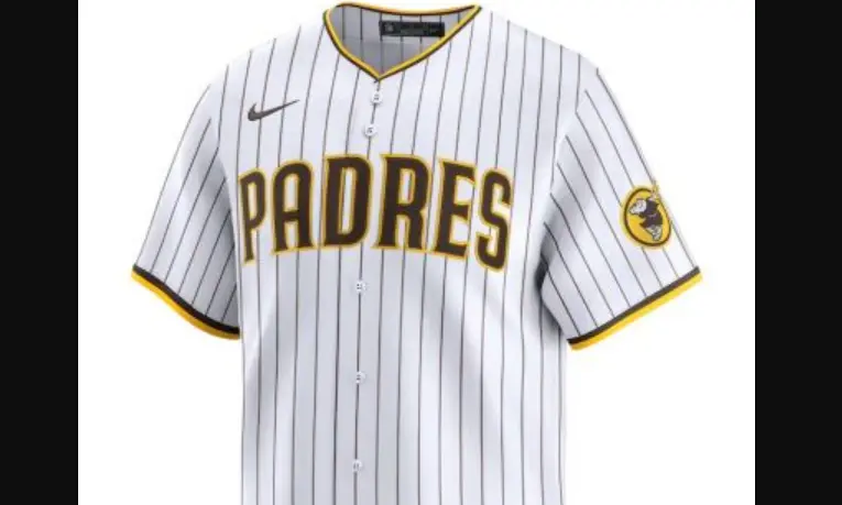 Modern San Diego Padres white jersey with brown pinstripes and gold-outlined ‘PADRES’ lettering, featuring the swinging friar patch on the sleeve