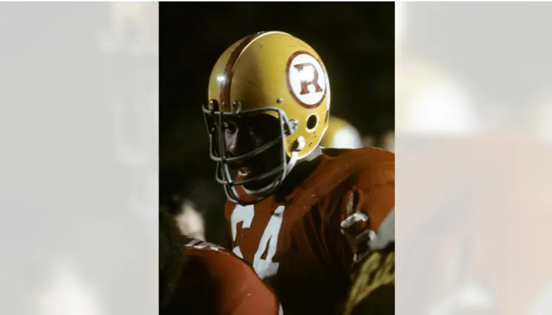 Close-up of a Washington Redskins player from the 1970–1980 era wearing a burgundy jersey and gold helmet featuring the bold 'R' logo, representing the 'Over the Hill Gang' period under coach George Allen